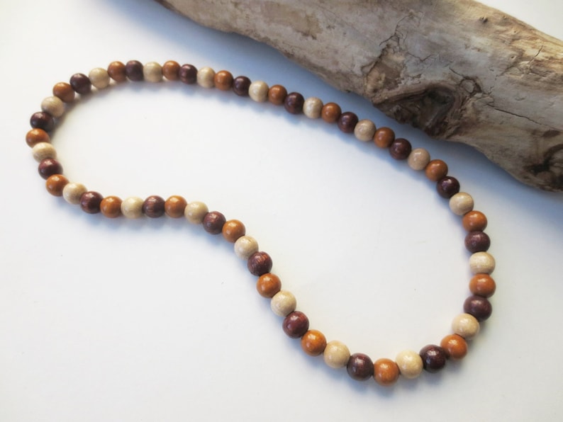 May include: A brown, beige, and cream wooden bead necklace. The beads are round and have a natural wood finish.
