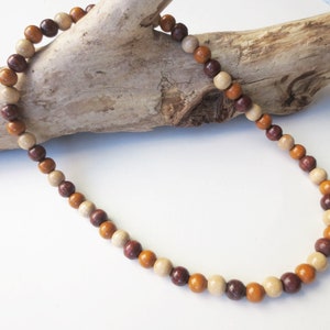 May include: A wooden bead necklace with brown, beige, and orange beads.