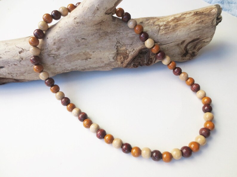 May include: A wooden bead necklace with brown, beige, and orange beads.