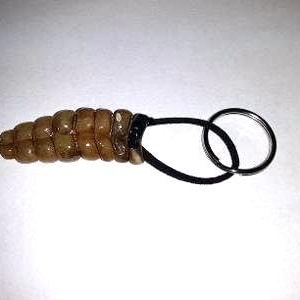 May include: A brown rattlesnake tail keychain with a black elastic loop and a silver key ring.