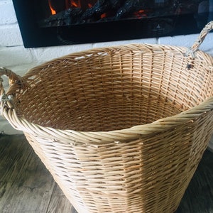 May include: A large, natural woven wicker basket with two handles. The basket is empty and has a light brown color.