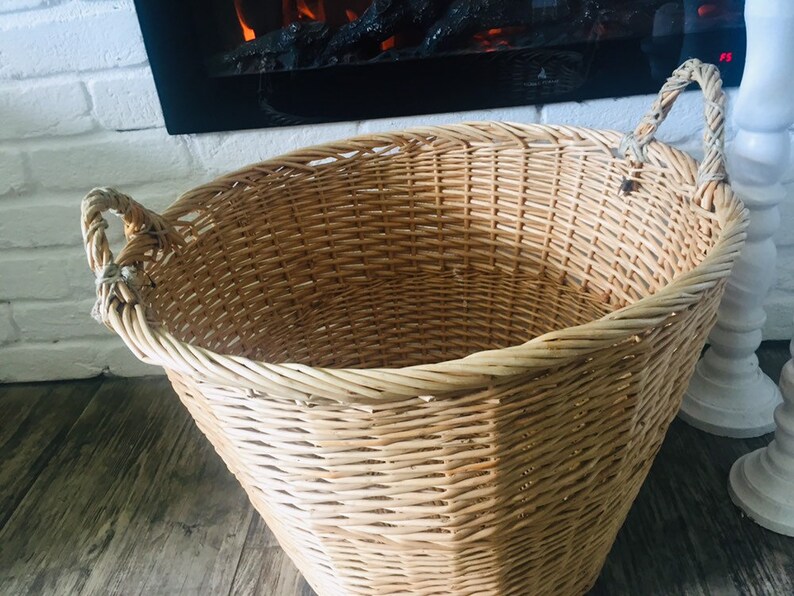 May include: A large, natural woven wicker basket with two handles. The basket is empty and has a light brown color.