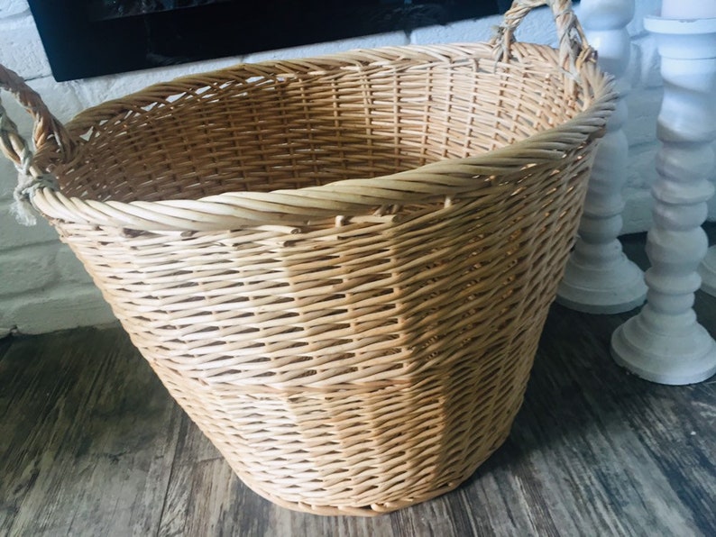 May include: A large, natural woven wicker basket with two handles. The basket is light brown and has a rounded bottom.