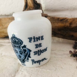 Op de afbeelding: Witte keramische pot met een blauw-wit ontwerp. De pot heeft de tekst "Fine de Dijon Poupon" op de voorkant.