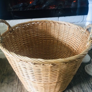 May include: A large, natural woven wicker basket with two handles. The basket is empty and has a light brown color.