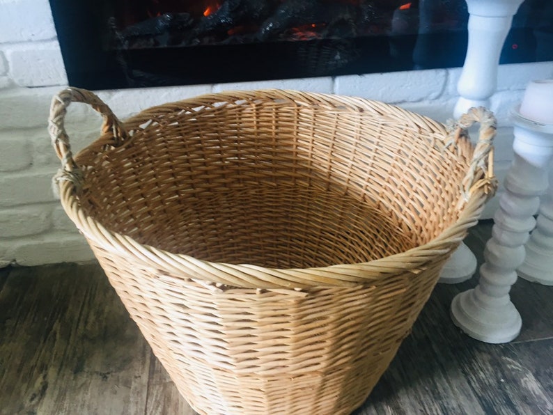 May include: A large, natural woven wicker basket with two handles. The basket is empty and has a light brown color.