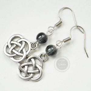 Könnte beinhalten: Silberne Ohrringe mit keltischem Knoten und schwarzen Edelsteinperlen.