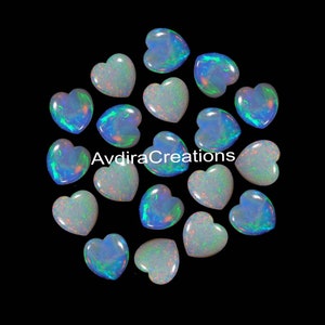 Puede incluir: Una colección de 15 piedras preciosas de ópalo en forma de corazón iridiscente. Los ópalos son una mezcla de blanco y azul con destellos de verde y arcoíris.