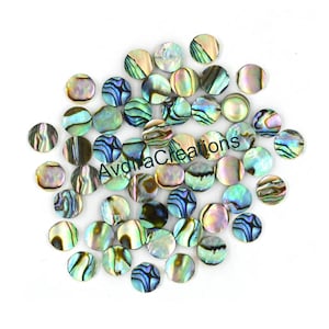 Könnte beinhalten: Eine Sammlung von irisierenden Abalone-Muschel-Cabochons in runder Form. Die Cabochons haben einen Durchmesser von etwa 2,5 cm und sind in verschiedenen Farben erhältlich, darunter Grün, Blau, Lila und Gold.