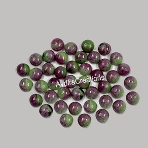 Könnte beinhalten: Eine Sammlung von 30 runden, grünen und rosafarbenen Edelstein-Cabochons. Die Cabochons sind glatt und poliert, mit einer Vielzahl von Grün- und Rosatönen.