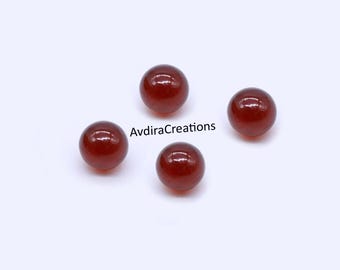 May include: Four polished, round, red-brown gemstone beads. The beads are evenly spaced against a white background. The text "AvdiraCreations" is visible on the image.