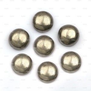 Pode incluir: Sete cabochões redondos, de cor prateada, metálicos, com textura martelada. Os cabochões estão dispostos em círculo sobre um fundo branco.