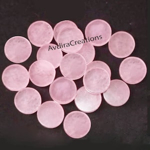 May include: A collection of 15 pink round glass cabochons. The cabochons are smooth and have a slight sparkle. The cabochons are all the same size and shape.