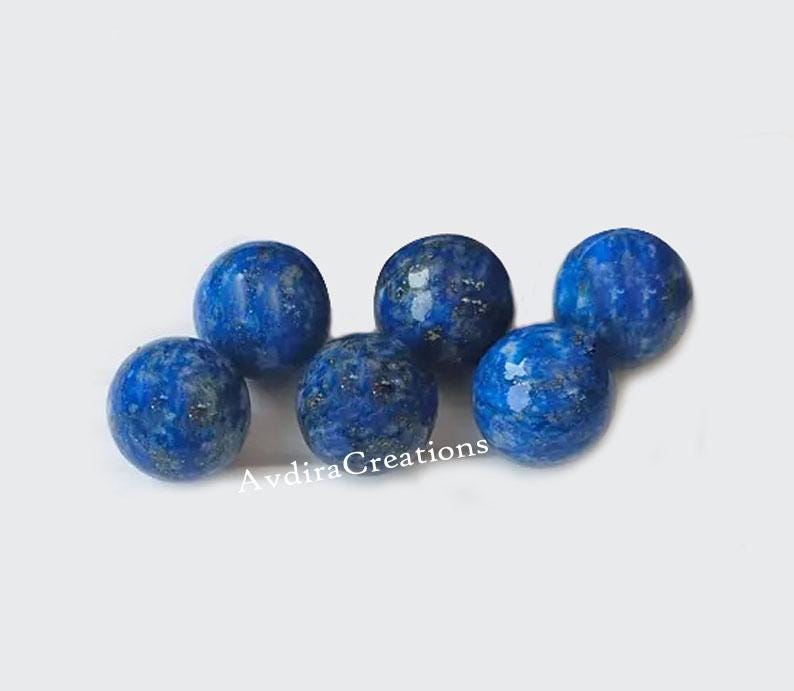 May include: Six round, blue lapis lazuli beads with gold flecks. The beads are approximately 1 inch in diameter.