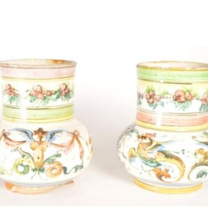 May include: Two decorative ceramic vases. Each vase features a bulbous body and a cylindrical neck. The vases are painted with floral and mythical creature designs in a palette of yellow, green, pink, and blue.