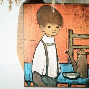 May include: A vintage painting on a wooden panel depicts a young person with brown hair and a white shirt with suspenders. The background features an orange wall, a blue table, and a brown teapot. The artwork has a mid-century modern style.