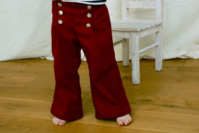 Pantalón infantil en alambique marítimo, pantalón marinero Fiete en rojo oscuro-burdeos, con pierna ancha, babero marinero derecho e izquierdo con botones. imagen 1