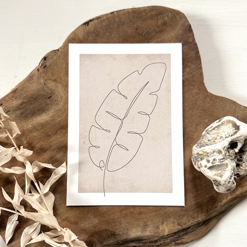 May include: A minimalist line drawing of a single leaf on a beige background. The leaf is drawn in a continuous line, creating a simple and elegant design.