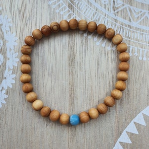 Könnte beinhalten: Ein Holzperlenarmband mit einem hellblauen Edelsteinperle. Das Armband besteht aus natürlichen Holzperlen und hat ein schlichtes Design.