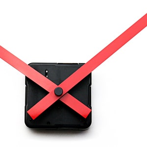 May include: A black clock mechanism with red clock hands. The hands are crossed over each other.