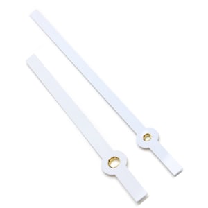 May include: Two white clock hands with gold centers. The hands are long and thin, and they are designed for a clock face.