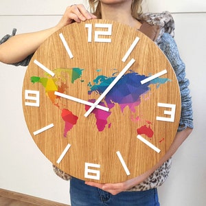 Op de afbeelding: Een houten klok met een regenboog wereldkaart ontwerp en witte cijfers en wijzers. De klok heeft een diameter van 30 cm.