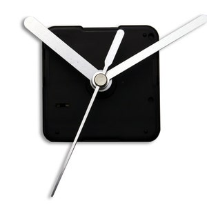 May include: A black clock mechanism with white hands. The hands are in a position to show the time as 12:00.