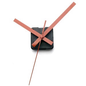 May include: A set of clock hands with a black clock mechanism. The hands are made of red metal and are designed for a standard clock face.