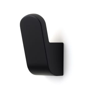 Puede incluir: Un gancho de pared negro mate con un diseño curvo. El gancho tiene una parte superior redondeada y una base rectangular, creando una estética moderna y minimalista. El gancho está diseñado para montarse en una pared.