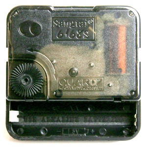 May include: A clear, rectangular quartz clock movement with the text "Sangtai 6468S" and "QUARTZ". The black plastic casing holds a battery and gears. The bottom reads "USE ALKALINE BATTERIES" and "1.5V".