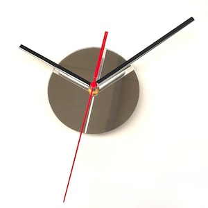 May include: A modern wall clock with a reflective silver face and black and red hands. The hour and minute hands are black with silver accents, and the second hand is a bright red. The clock has a minimalist design.