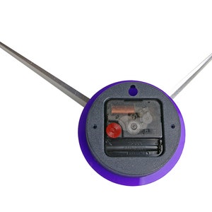 May include: A purple clock face with a silver clock hand and a black clock mechanism. The clock face has a hole in the centre.