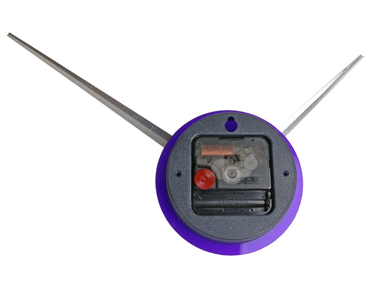 May include: A purple clock face with a silver clock hand and a black clock mechanism. The clock face has a hole in the centre.