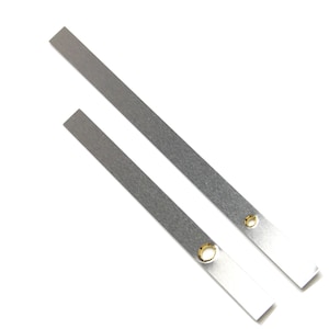 May include: Two silver metal clock hands with holes for mounting. The hands are different lengths.