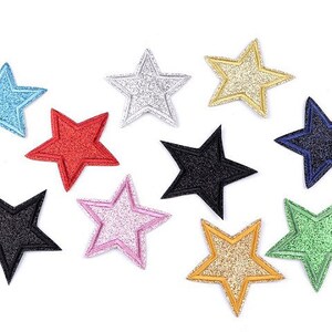 Könnte beinhalten: Zehn sternförmige Bügelbilder in verschiedenen Farben, darunter Schwarz, Blau, Grün, Gold, Rosa, Rot und Silber. Die Sterne sind alle gleich groß und haben eine leicht erhabene, strukturierte Oberfläche.