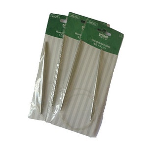 Könnte beinhalten: Drei Packungen silberner Rundstricknadeln. Die Nadeln sind in durchsichtigem Plastik mit einem weiß-grünen gestreiften Hintergrund verpackt. Die Packungen sind mit dem Text "Größl" und "Rundstricknadel 6.0 mm - 40 cm" beschriftet.