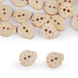Könnte beinhalten: Eine Sammlung von Holz-Marienkäfer-Knöpfen mit schwarzen Punkten und zwei Löchern zum Nähen. Die Knöpfe sind auf einer weißen Oberfläche verstreut.