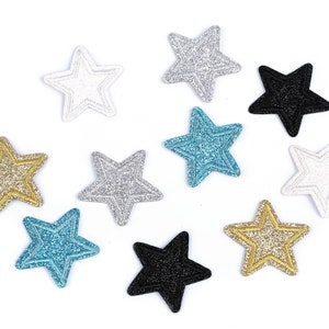 Könnte beinhalten: Zehn glitzernde sternförmige Verzierungen in verschiedenen Farben, darunter Gold, Silber, Weiß, Schwarz, Blau und Türkis.