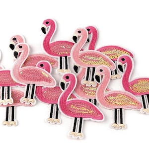 Könnte beinhalten: Ein Set mit neun pinkfarbenen Flamingo-Aufnähern mit Pailletten. Die Aufnäher sind in verschiedenen Posen und Größen.