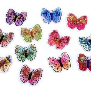 Könnte beinhalten: Sortiment von 10 bunten Schmetterlings-Aufnähern zum Bügeln. Die Schmetterlinge bestehen aus Pailletten und haben eine Vielzahl von Farben, darunter Blau, Grün, Pink, Orange und Lila.