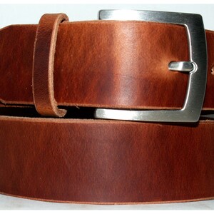 May include: A brown leather belt with a silver buckle. The belt is folded in half, showing the buckle and the leather.