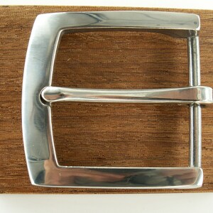 May include: A silver metal belt buckle with a smooth, polished finish.