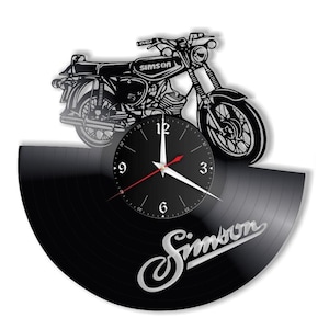 Könnte beinhalten: Eine schwarze Schallplattenuhr mit einem silbernen Simson-Logo und einer schwarz-weißen Silhouette eines Motorrads. Das Zifferblatt der Uhr ist schwarz mit weißen Zahlen und silbernen Zeigern.