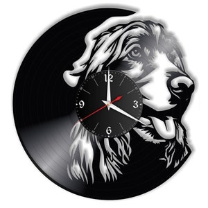 May include: Black vinyl record clock with a white silhouette of a dog's head. The clock face is black with white numbers and hands.