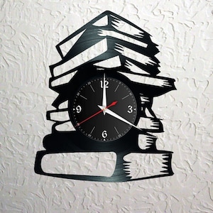 Può includere: Orologio in vinile nero a forma di pila di libri. Il quadrante dell'orologio ha lancette nere e numeri bianchi.