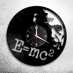 May include: A black vinyl record clock featuring a silhouette of Albert Einstein with the famous equation "E=mc2" printed below. The clock face is black with white numbers and hands.