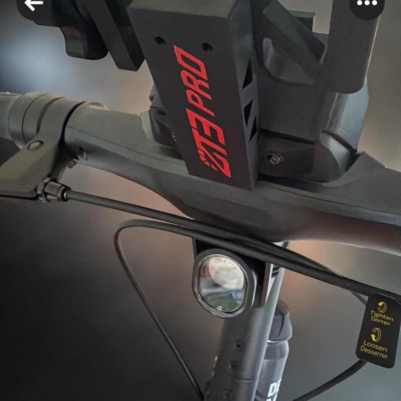 May include: Black electric scooter handlebar with a headlight and a bracket that reads "ZTE PRO" in red. The handlebar also has a small light and a lever.