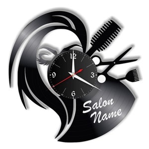 Könnte beinhalten: Schwarze Schallplattenuhr mit einer Silhouette eines Frauenkopfes, Haaren und Salonwerkzeugen wie Schere, Kamm und Föhn. Das Zifferblatt der Uhr ist schwarz mit weißen Zahlen und Zeigern. Der Text "Salon Name" ist auf die Schallplatte gedruckt.