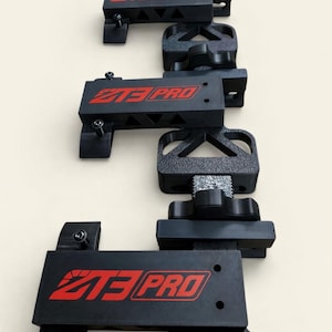 Könnte beinhalten: Eine vertikale Anordnung schwarzer Metallhalterungen mit dem roten Text "Z3 PRO". Die Halterungen haben verschiedene Formen und Größen, darunter dreieckige und rechteckige Designs. Das Bild ist vor einem hellbeigen Hintergrund aufgenommen.