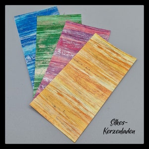 Könnte beinhalten: Vier Blätter Dekorpapier mit Holzmaserung in Blau, Grün, Rosa und Gelb. Das Papier ist perfekt für Bastelarbeiten, Scrapbooking und Kartenherstellung.